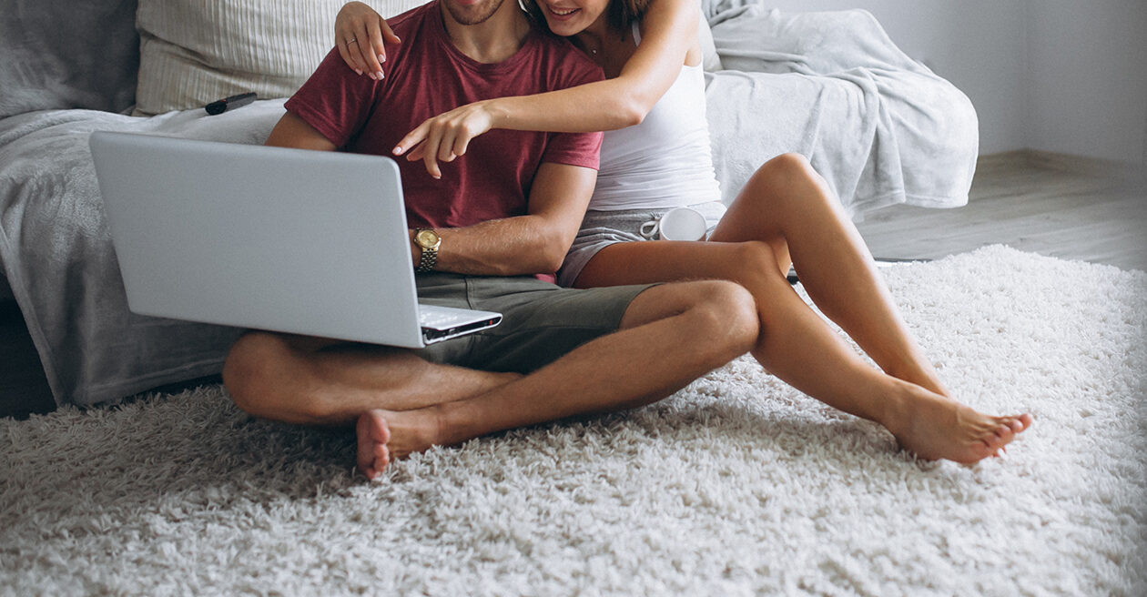 Couple at home together sitting on floor with computer